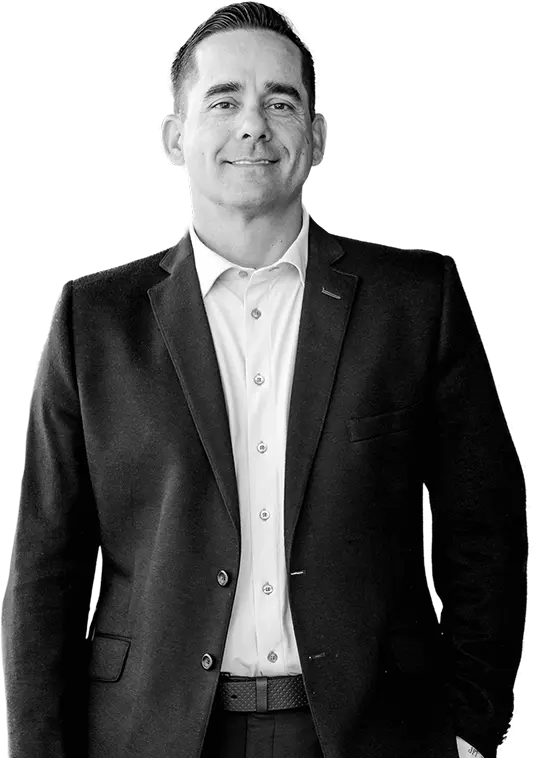 A man in a dark suit jacket and white dress shirt smiling.